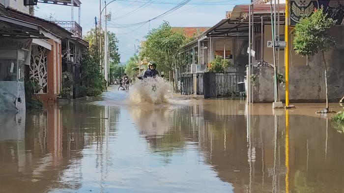 TERJANG BANJIR - Warga menerjang banjir di Desa Kumupulrejo Kecamatan Kaliwungu Kendal, Jumat (16/1/2026). Selain ada tanggul yang jebol di Kali Waridin, banjir terjadi akibat hujan deras yang mengguyur semalam.