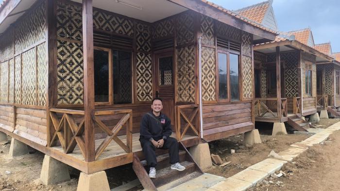KAMPUNG KDM - Seorang warga duduk di satu di antara deretan rumah panggung bernuansa adat Sunda di Desa Panyindangan, Kecamatan Sukatani, Kabupaten Purwakarta, Jawa Barat, Sabtu (17/1/2026). Deretan rumah ini akan dinamakan Kampung KDM yang merupakan bantuan dari Pemerintah Provinsi Jawa Barat.Dinding bilik dari anyaman bambu, atap genteng, serta tiang-tiang kayu yang kokoh menjadi penanda lahirnya sebuah permukiman baru bernama Kampung KDM.Pantauan Tribunjabar.id, Jumat (16/1/2026) sore, sebanyak 40 unit rumah bantuan yang diperuntukkan bagi warga terdampak bencana pergerakan tanah telah selesai dibangun dan siap dihuni. Rumah-rumah itu berdiri di lahan milik desa seluas 5,01 hektare, berlokasi di Kampung Pasir Cabe, Desa Panyindangan.