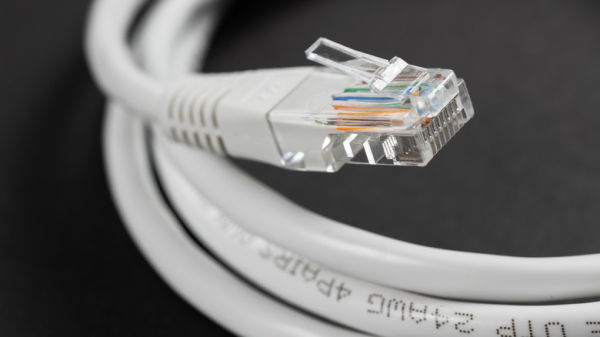 Close-up macro shot of a white RJ45 Ethernet cable on a dark table