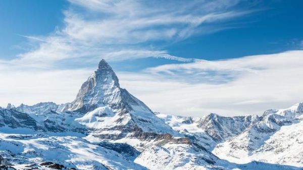 This may contain: the mountains are covered in snow and there is a blue sky with clouds above them