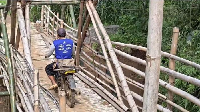 JEMBATAN RUSAK - Warga saat melintasi jembatan darurat di Dusun Minging Desa Grogol Kecamatan Sawoo, Kabupaten Ponorogo, Jatim, Senin (19/1/2026). Jembatan kedua ini ambrol total pada Maret 2025. Total ada 3 jembatan rusak di Desa Grogol, akses roda 4 tertutup total.