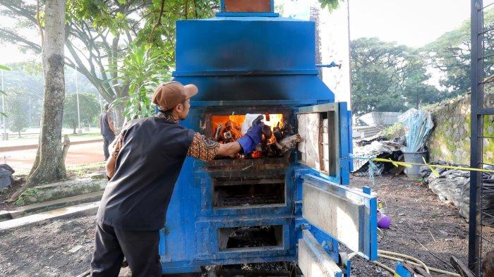 MESIN INSINERATOR - Seorang petugas saat mengoperasikan mesin insinerator tenaga air di kawasan GOR Saparua, Kamis (8/5/2025).