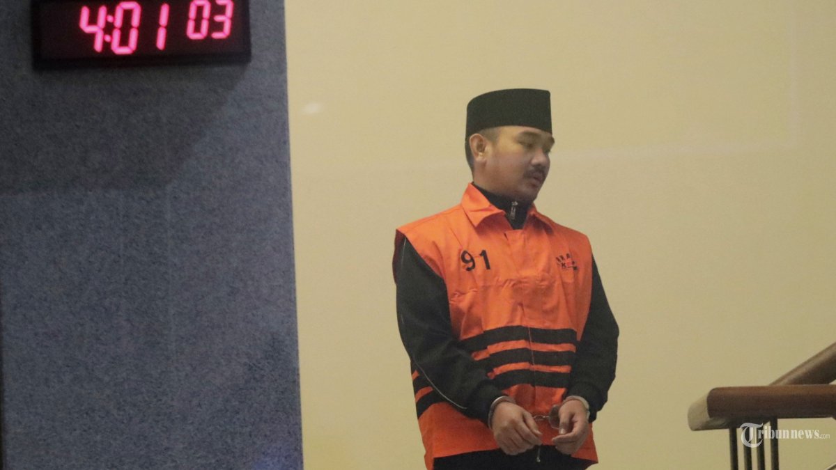 OTT KPK - Bupati Kabupaten Bekasi Ade Kuswara Kunang mengenakan rompi tahanan usai terjaring operasi tangkap tangan (OTT) di Gedung Merah Putih KPK, Jakarta, Sabtu (20/12/2025). KPK resmi menahan Bupati Kabupaten Bekasi Ade Kuswara Kunang (tengah) bersama  Kepala Desa Sukadami, Kecamatan Cikarang Selatan M Kunang (kanan) dan Pihak Swasta Sarjan terkait tindak pidana korupsi suap ijon proyek di Kabupaten Bekasi. TRIBUNNEWS/IRWAN RISMAWAN