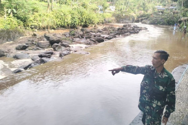 Seorang anggota TNI menunjukkan aliran sungai bercampur lumpur di Desa Limpakuwus, Kecamatan Sumbang, Kabupaten Banyumas, Jawa Tengah, Sabtu (24/1/2026). Foto: Relawan/HO/Antara