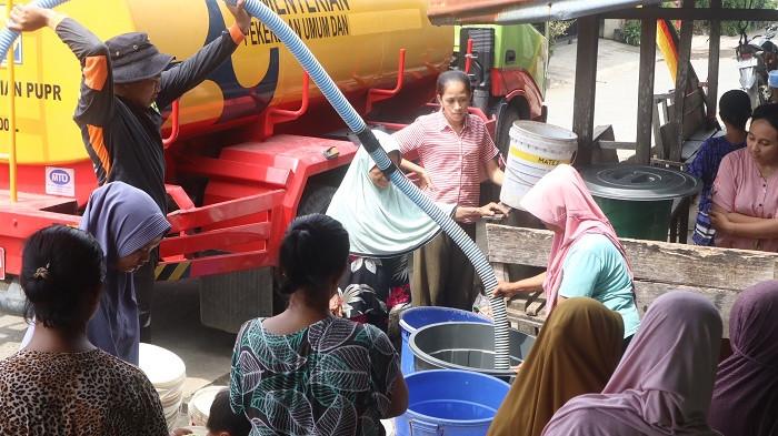 KEKERINGAN DI PADANG: Warga RT 001 RW 008, Kelurahan Pasa Ambacang, Kecamatan Kuranji, Kota Padang, Selasa (27/1/2026) siang menampung air bersih. Puluhan ember, baskom, hingga jerigen berbagai ukuran berjejer rapi di pinggir jalan, silih berganti menampung kucuran air bersih dari selang tangki menuju tedmond biru yang disediakan sebagai bak penampung sementara.