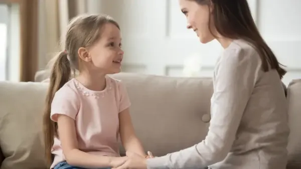 woman holding hands and talking to her daughter