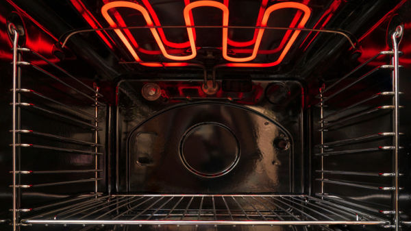 Looking inside an empty, black oven with the heating coils on and red-hot