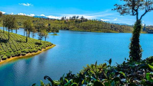 This may contain: a large body of water surrounded by lush green hills and trees on the side of it