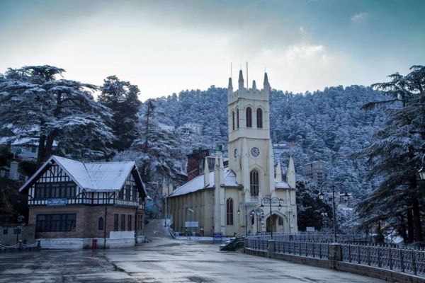 This may contain: an old church in the middle of a snowy town with trees and mountains behind it