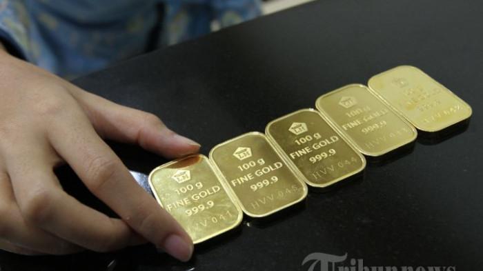 HARGA EMAS ANTAM - Customer service Bank BNI Syariah menunjukkan logam mulia emas ukuran 100 gram di banking hall di Jakarta Selatan, Senin (16/12/2013).