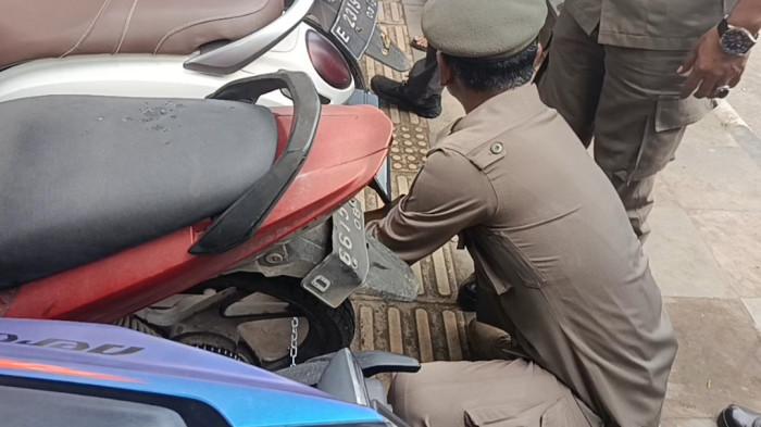 MOTOR DIGEMBOK - Satu per satu sepeda motor yang nekat 'numpang' di atas trotoar depan CSB Mall, Kota Cirebon, tak lagi dibiarkan. Tanpa banyak peringatan, petugas datang, rantai dikaitkan, gembok dikunci. Trotoar yang selama ini berubah fungsi menjadi lahan parkir pun mulai dikembalikan ke khitahnya. Pemandangan itu terlihat jelas pada Selasa (3/2/2026) siang.