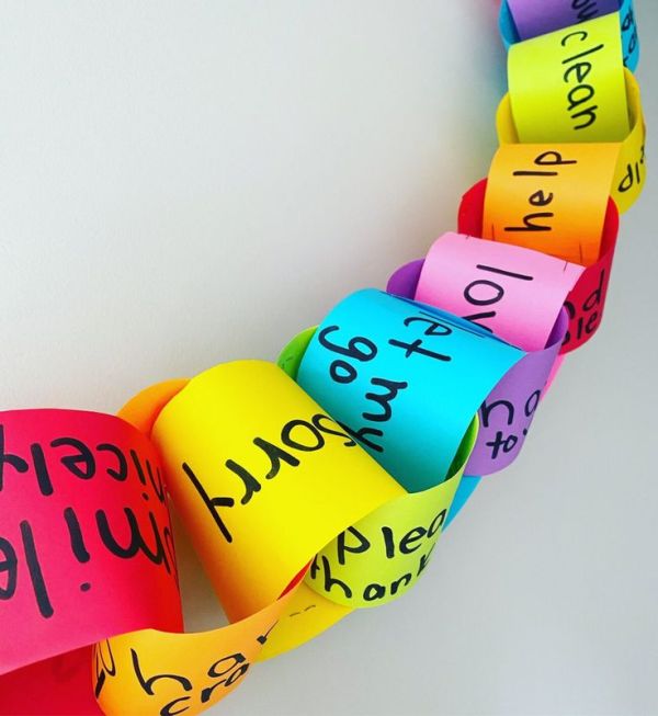 This may contain: colorful paper hearts with words written on them hanging from a white wall in the shape of a heart