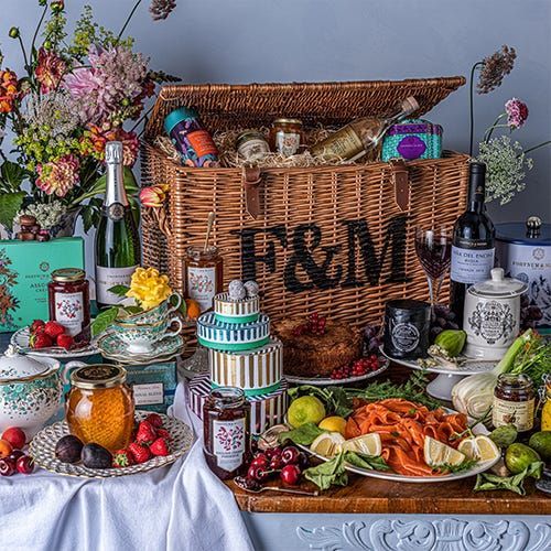This may contain: a table topped with lots of different types of food and drinks next to a wicker basket
