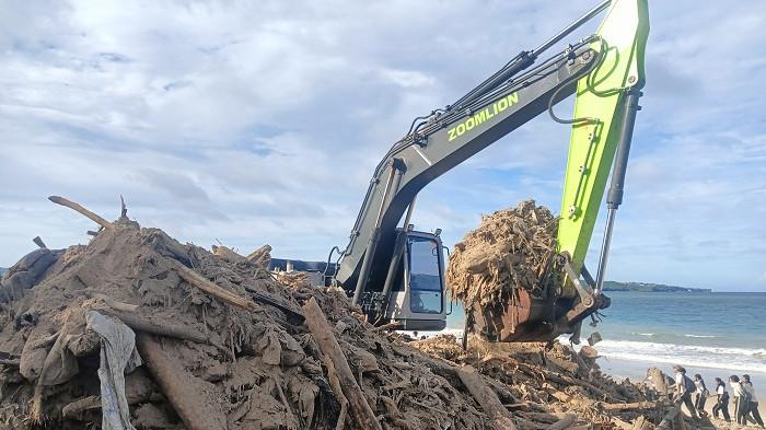BERSIH-BERSIH - Eskavator meminggirkan sampah kayu bercampur sampah plastik ke pesisir pantai Kedonganan hingga membuat gunungan pada aksi bersih-bersih sampah laut di Pantai Kedonganan, Kecamatan Kuta, Kabupaten Badung, Jumat (6/2).