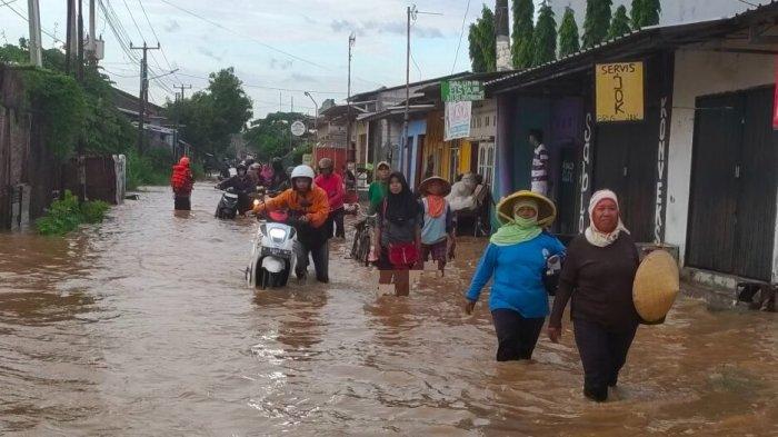 Warga mendorong sepeda motornya yang mogok saat menerjang banjir yang terjadi di Kabupaten Cirebon, Jumat (24/1/2025) pagi.