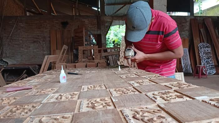 SENI MENGUKIR - Perajin di Desa Pedosawalan RT 09 RW 03, Kecamatan Kalinyamatan, Kabupaten Jepara sedang mengukir karya ukir kaligrafi, Minggu (8/2/2026). Karya produk Nur Art Kaligrafi Jepara kini sudah tembus ke panggung dunia.
