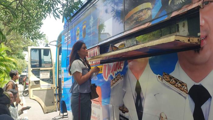 BAYAR PAJAK - Seorang wajib pajak menyerahkan uang ke petugas Samsat untuk membayar kewajiban pajaknya  di Samsat Keliling Simpang Lima, Rabu (7/1/2026). 