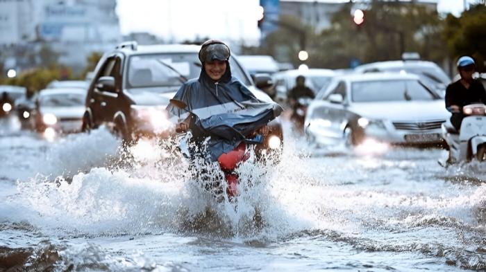 MENEMBUS BANJIR- Seorang wanita pengendara motor berusaha menembus genangan banjir yang menyebabkan ruas jalan tenggelam di sebuah kawasan perkotaan.