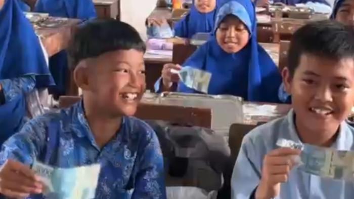 MBG SPESIAL : Para siswa penerima manfaat MBG distribusi SPPG Pangeleyan, Kecamatan Tanah Merah, Kabupaten Bangkalan sumringah ada uang Rp 50 ribu yang diselipkan pada ompreng Makan Bergizi Gratis, Rabu (11/2/2026). Uang yang disedekahkan Haji Her Pamekasan total sejumlah Rp 93.850 juta yang disebar untuk 1.877 ompreng