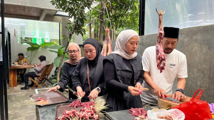 BAKAR SATE - Agung Purnama, salah satu cucu atau generasi ketiga pemilik Sate Hadori bersama saudarinya, Vitta Sukmawatie (kedua kiri) saat mengiris daging kambing di Sate Hadori, Jalan Natuna, Kota Bandung, Sabtu (14/2/2026).