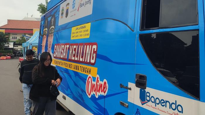 BAYAR PAJAK - Seorang wajib pajak menyerahkan uang ke petugas Samsat untuk membayar kewajiban pajaknya  di Samsat Keliling Simpang Lima, Kota Semarang, Rabu (7/1/2026). 