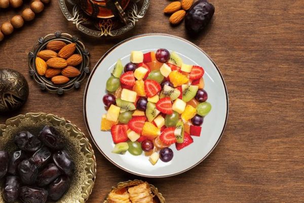 This may contain: fruit salad on a white plate surrounded by other fruits and nuts, including almonds