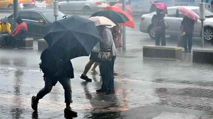 HUJAN SEDANG- Sejumlah orang tampak menggunakan payung untuk melindungi diri dari cuaca hujan sedang yang melanda wilayahnya.