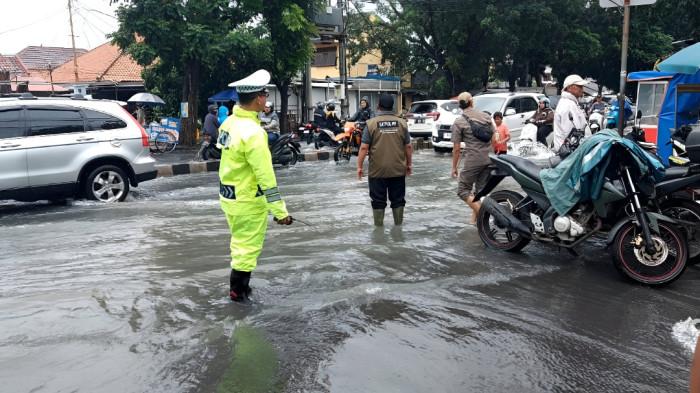 BANJIR- Polisi lalu lintas tampak mengatur arus lalu lintas di jalanan yang tergenang banjir akibat hujan deras.