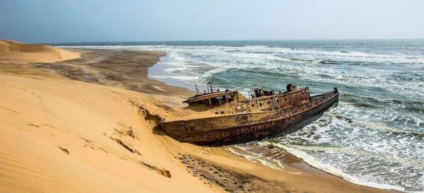 This may contain: an old boat sitting on top of a sandy beach near the ocean's edge