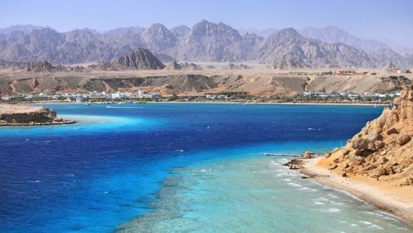This may contain: an aerial view of the blue waters and mountains in oman, with boats on the water