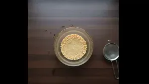 Chana dal being rinsed and soaked in a bowl of water to soften before cooking.