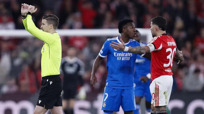 RASISME - Winger Real Madrid, Vinicius Junior (tengah) diduga mendapatkan tindakan rasisme dari pemain Benfica selama pertandingan play-off babak 16 besar Liga Champions, pada Rabu (18/2/2026) dini hari WIB. Vinicius Jr langsung melapor ke wasit dan pertandingan dijeda 10 menit karena mengaktifkan protokol anti-rasisme UEFA.