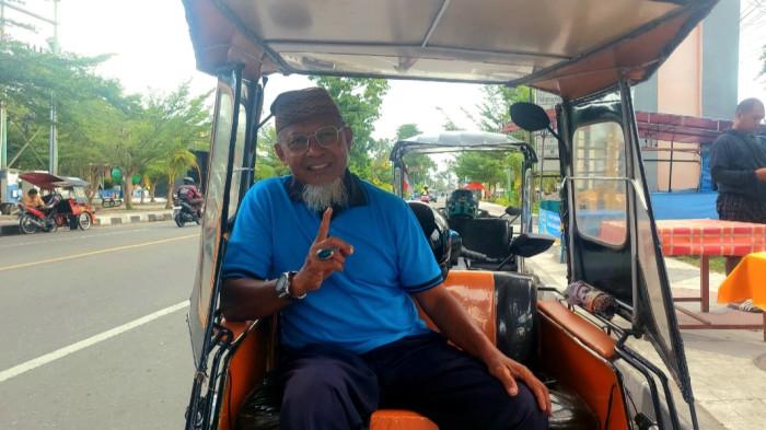 HUMAN INTEREST — Vecky van Gobel duduk manis menanti penumpang di bawah Menara Keagungan Limboto, Jumat (20/2/2026) pagi. Vevky merupakan pensiunan PNS.