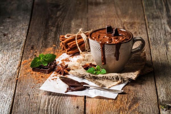 This may contain: hot chocolate in a mug with cinnamon and star anise on the side, surrounded by other ingredients