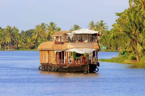 This may contain: a house boat floating on top of a river next to palm tree covered shore line