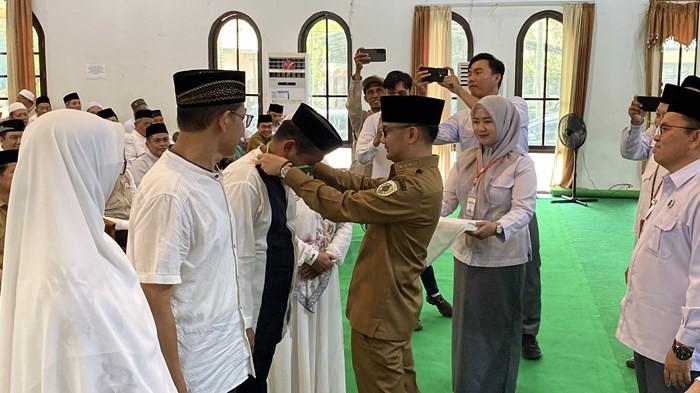 MENYEMATKAN - Wali Kota Palangka Raya Fairid Naparin menyematkan tanda kartu peserta kepada calon jamaah haji saat pembukaan Bimbingan Manasik Haji Jamaah Reguler Tingkat Kota Palangka Raya Tahun 1447 H/2026 M di Aula Arafah Asrama Haji Palangka Raya, Senin (23/2/2026).