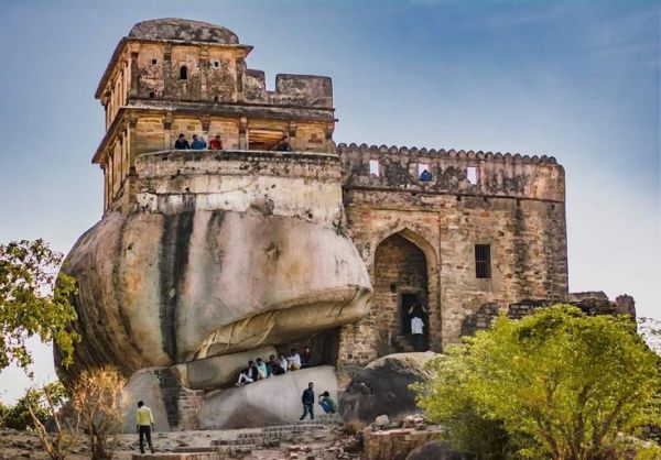 This may contain: people are standing on top of a rock formation in front of a castle like structure
