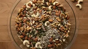 Bowl of mixed nuts and seeds on wooden table.