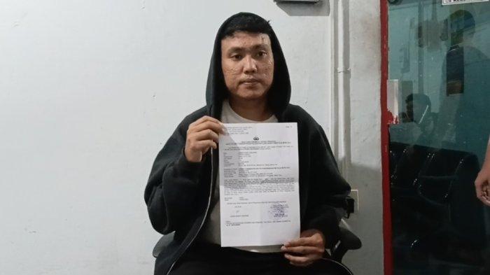 Pegawai SPBU korban dugaan penganiayaan aparat, Abud Mahbudin (28) saat menunjukkan surat laporan polisi atas kasus dialami, Pulogadung, Jakarta Timur, Senin (23/2/2026).