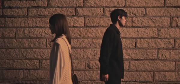 This may contain: two people standing in front of a brick wall with one person looking at the other