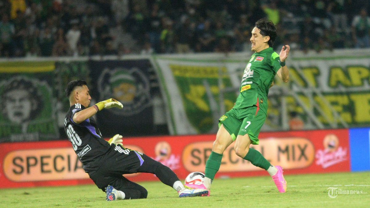 MENANG TIPIS - Pemain Persebaya Rivera (kanan) berhadapan  dengan Kiper PSM Makassar M Reza (kiri) pada pertandingan yang berlangsung di Stadion gelora Bung Tomo (GBT) Surabaya, Rabu (25/2/2026) malam. Pada laga pekan 23 BRI Super League ini pertandingan berakhir dengan kemenangan tuan rumah Persebaya dengan skor akhir 1-0. (SURYA/HABIBUR ROHMAN)