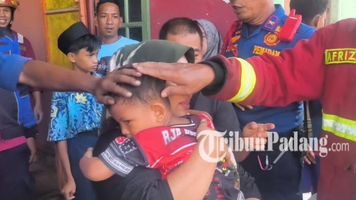 KEBAKARAN DI PADANG - Warga, Sherly saat mengendong sang anak usai ditemukan selamat saat bersembunyi di toko bangunan di samping rumahnya yang terbakar, Andalas, Kecamatan Padang Timur, Kota Padang, Rabu (25/2/2026). Sherly menggendong sang anak dengan erat sembari meneteskan air mata.