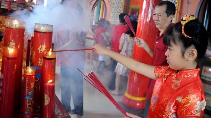 SEMBAHYANG IMLEK- Ilustrasi seorang bocah perempuan bersama keluarganya sedang sembahyang menyambut datangnya Tahun Baru Imlek.