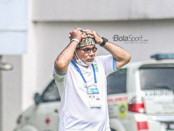 Pelatih Persela Lamongan, Iwan Setiawan, sedang memegangi peci yang melekat di kepalanya dalam laga pekan kelima Liga 1 2021 di Stadion Pakansari, Bogor, Jawa Barat, 28 September 2021.
