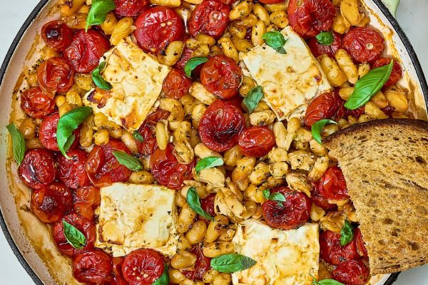 A skillet filled with baked feta cherry tomatoes white beans fresh basil leaves and a slice of toasted bread Credit: Photographer: Brittney Cottrell, Food stylist: Marianne Williams, Prop Stylist: Josh Hoggle