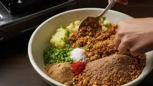 Mixing roasted makhana, potatoes, spices, and herbs in a bowl.