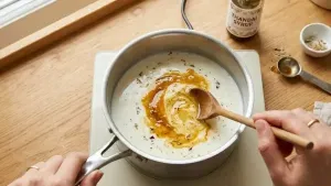 In a pan, take 1 cup full-cream milk and mix in 2–3 tablespoons of thandai syrup or powder until well combined.