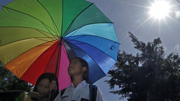 Pelajar menggunakan payung untuk berlindung dari sengatan matahari saat melintas di Jalan Agus Salim, Medan, beberpa waktu lalu. Memasuki hari ke empat pada awal tahun 2019 kondisi cuaca Kota Medan terasa panas menyengat, suhu mencapai 32 derajat celcius. TIBUN MEDAN/DANIL SIREGAR