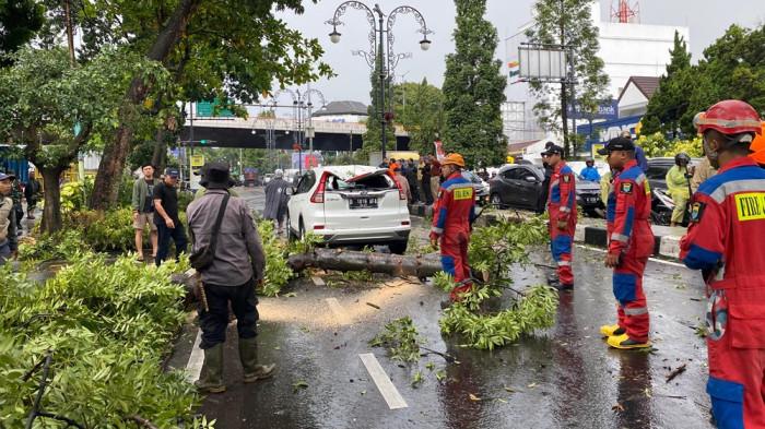 POHON TUMBANG- Petugas Damkar saat evakuasi pohon tumbang yang menimpa mobil di Dago, Rabu (4/3/2026). Pohon tumbang terjadi akibat hujan deras disertai angin kencang.