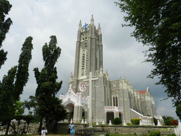 This may contain: a large church with tall steeples surrounded by trees and people standing in front of it